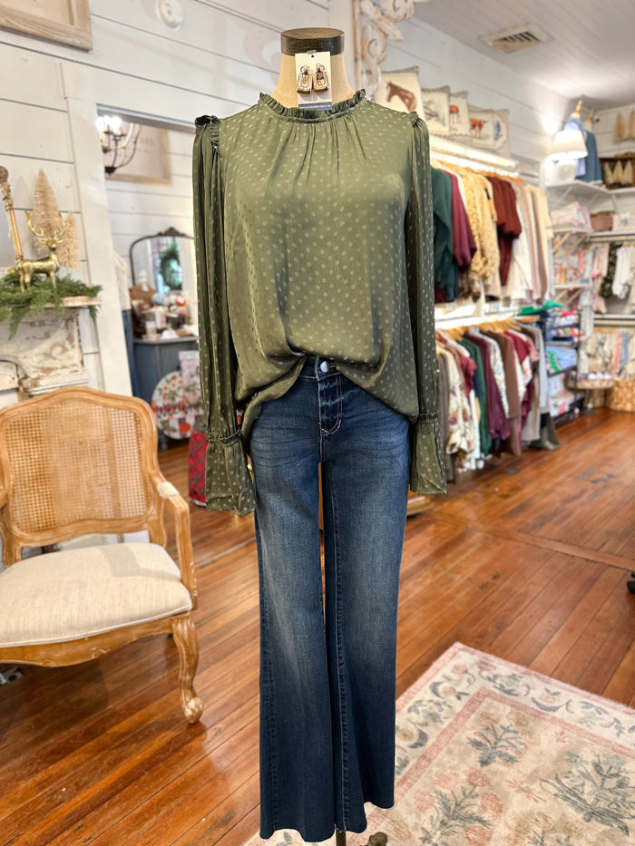 Mannequin wearing a green blouse and blue jeans in a store setting