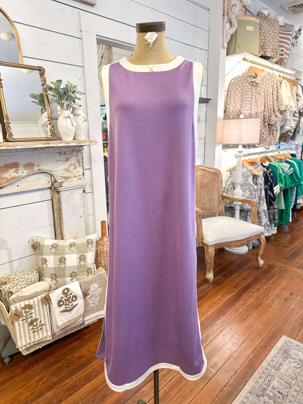 Purple dress on a mannequin in a store setting with various items in the background.