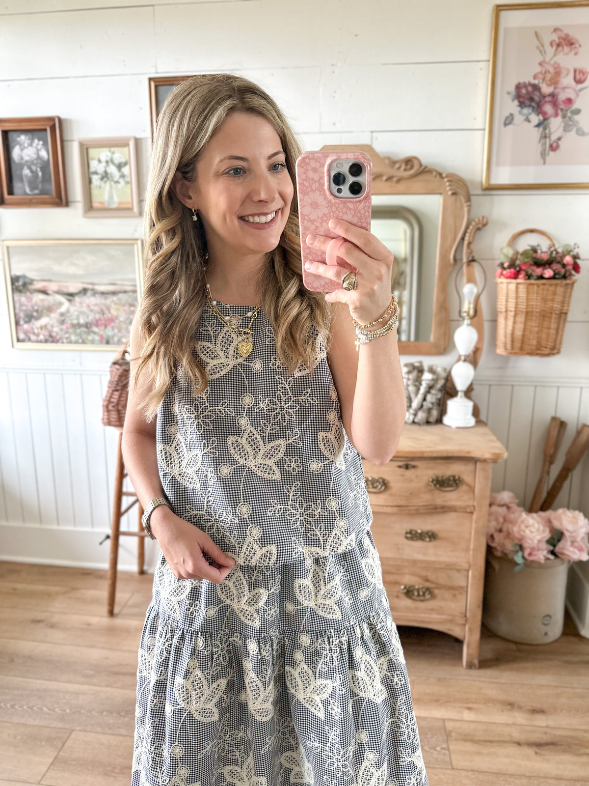 Woman taking a mirror selfie wearing a floral dress in a home setting.