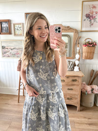 Woman taking a mirror selfie wearing a floral dress in a home setting.