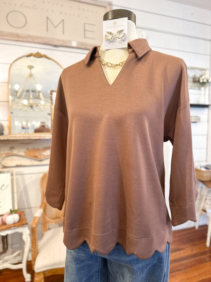 Brown soft top on a mannequin with a blurred indoor background