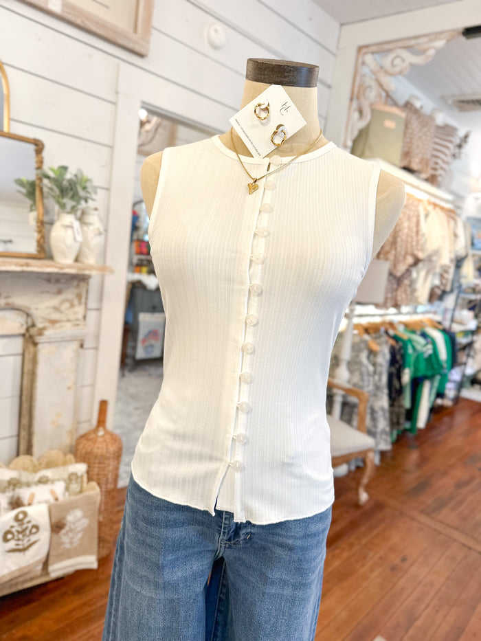 Mannequin wearing a white sleeveless blouse with blue jeans in a store setting