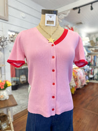 Pink cardigan top with red trim on a mannequin in a store setting