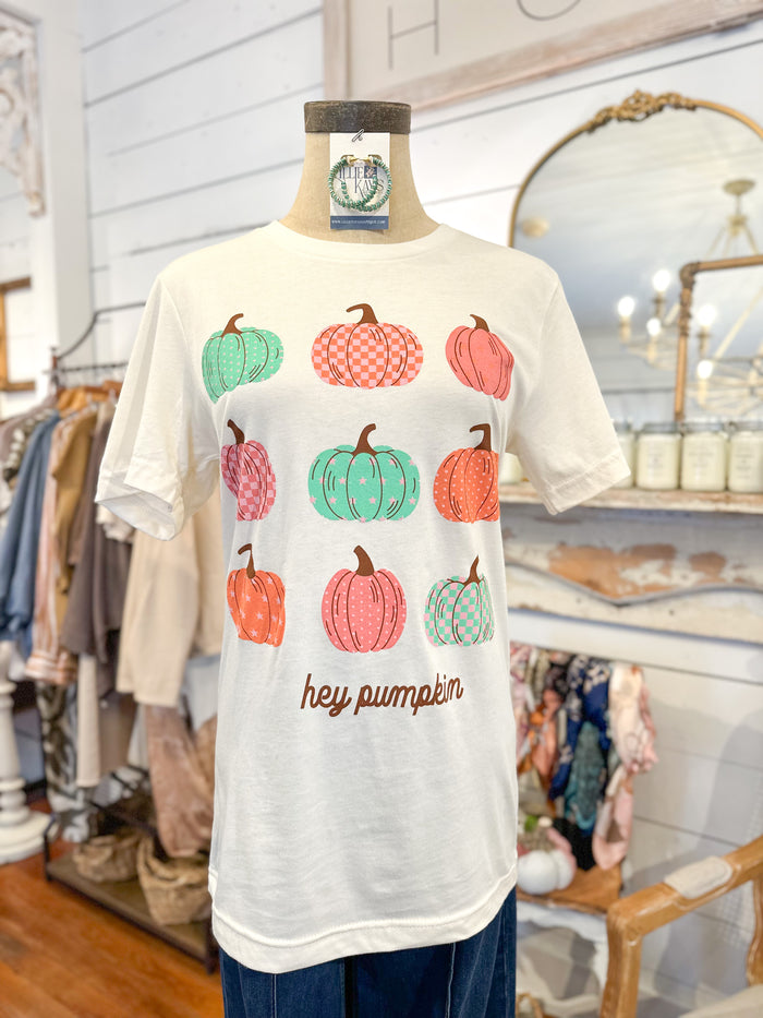 White t-shirt with colorful pumpkins and 'hey pumpkin' text on a mannequin in a store setting.