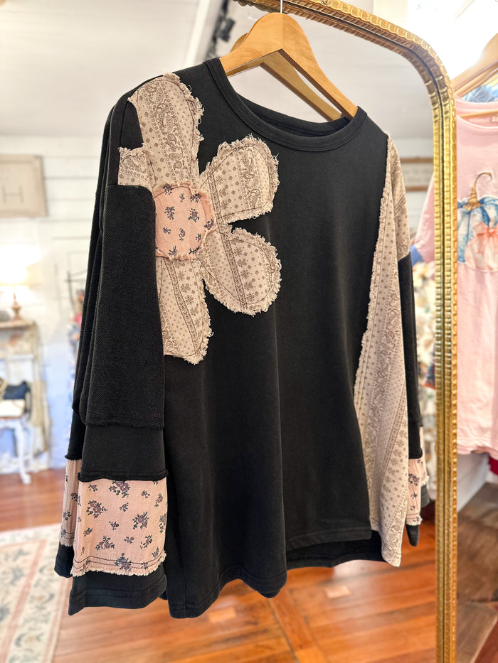 Black top with lace and floral details on a hanger