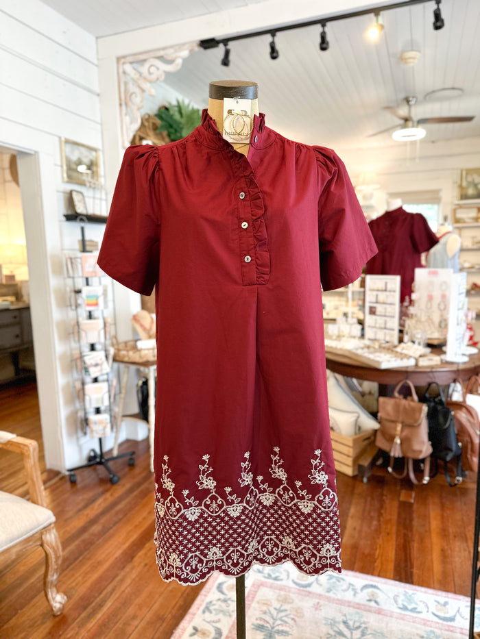 Red dress with white embroidery on a mannequin in a store setting