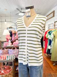Striped cardigan on a mannequin in a store setting with clothing racks and bags in the background.