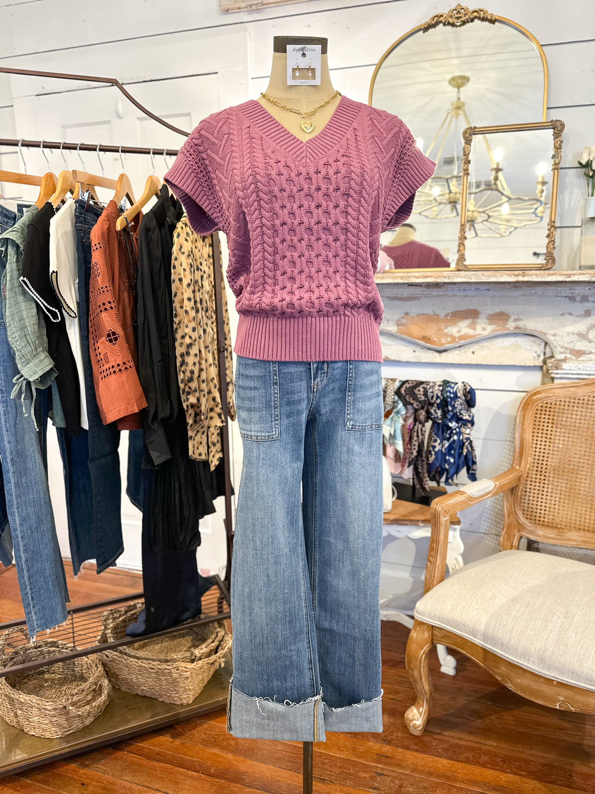 Mannequin wearing an orchid pink knitted top and blue jeans in a clothing store setting.