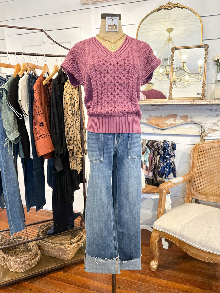 Mannequin wearing an orchid pink knitted top and blue jeans in a clothing store setting.