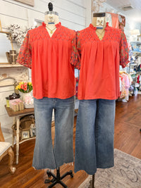 Two mannequins wearing coral tops and blue jeans in a store setting.