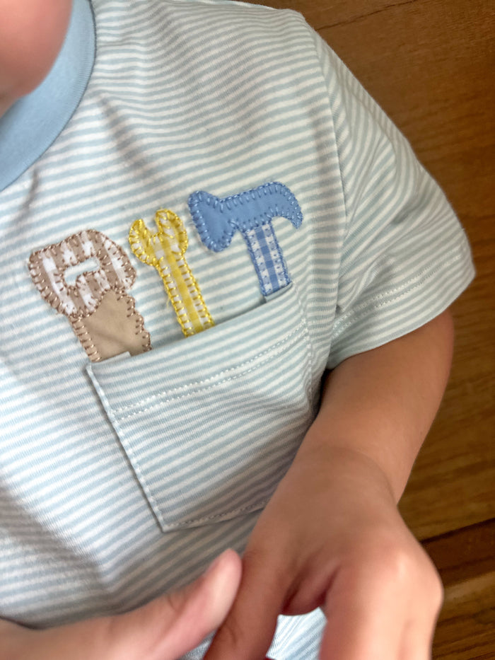 Close-up of a child's shirt with embroidered tools on top of pocket on top 