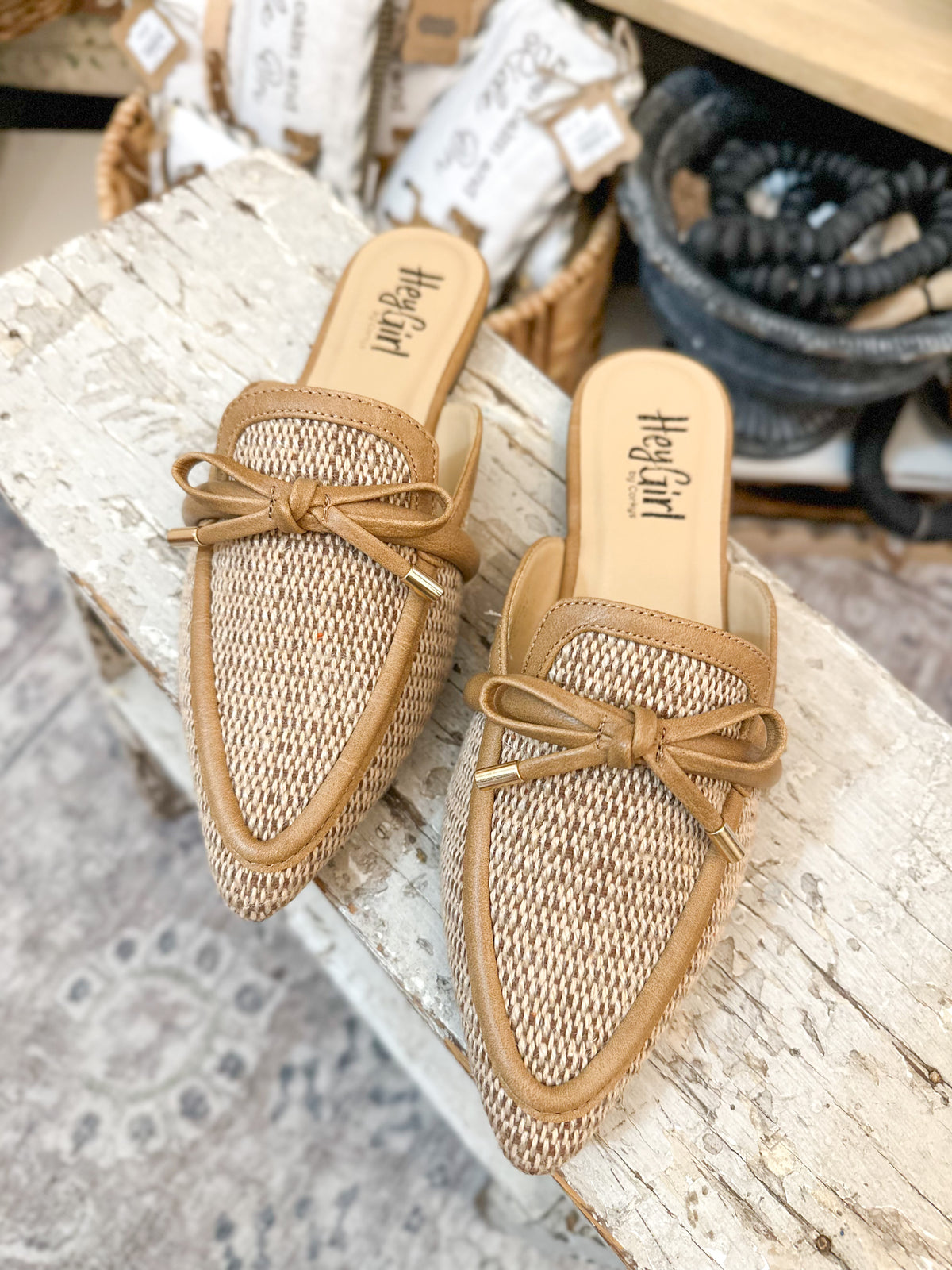 Pair of woven sandals with a bow on a wooden surface. corkys footwear 