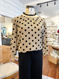 Mannequin wearing a beige sweater with black polka dots in a store setting