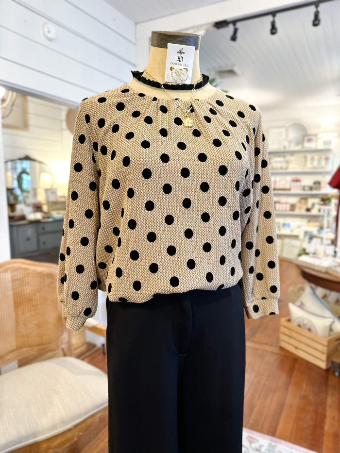 Mannequin wearing a beige sweater with black polka dots in a store setting
