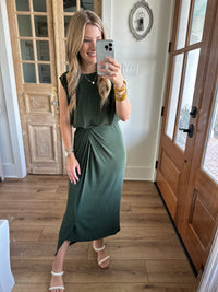 Woman taking a mirror selfie wearing a green dress in a home setting.