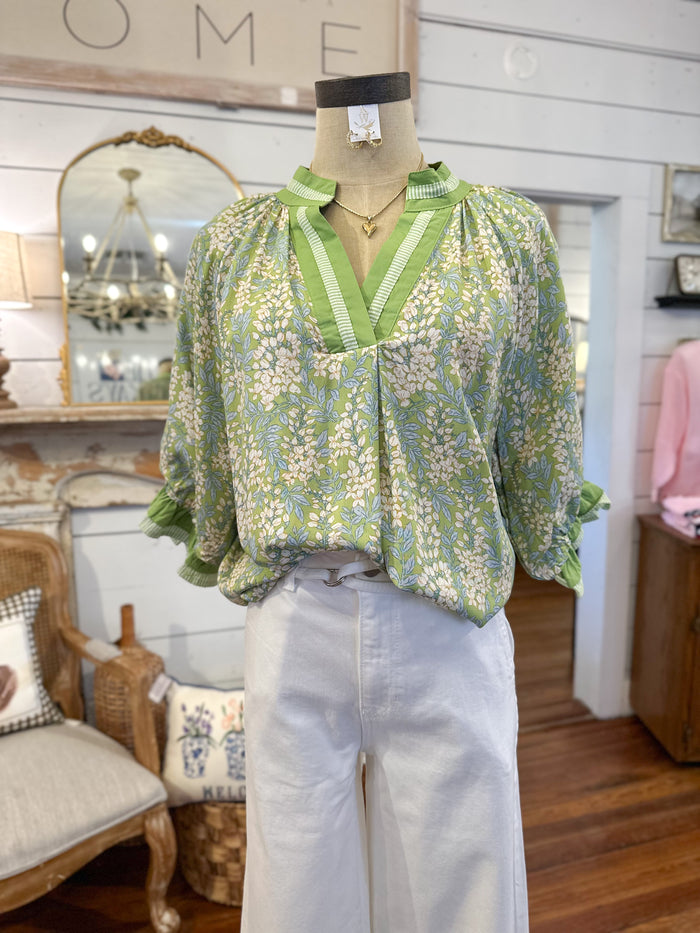 Mannequin wearing a green floral blouse in a store setting