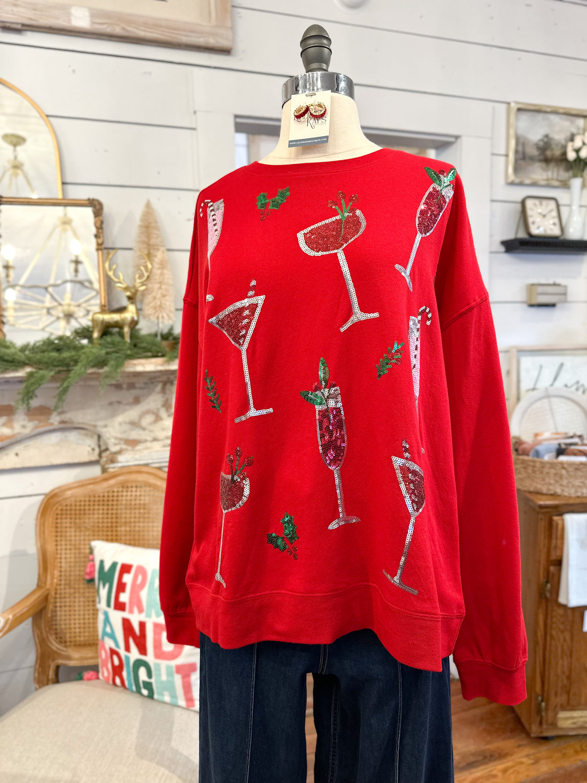 Red sweater with cocktail and berry pattern on a mannequin against a home decor background.