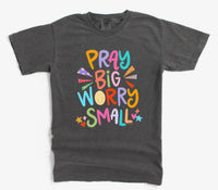 Dark gray t-shirt with colorful text 'Pray Big Worry Small' on a white background