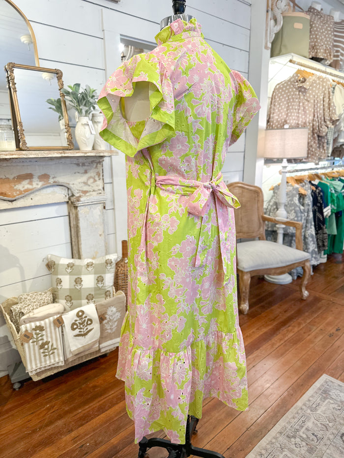 Floral dress on a mannequin in a store setting with various items in the background.