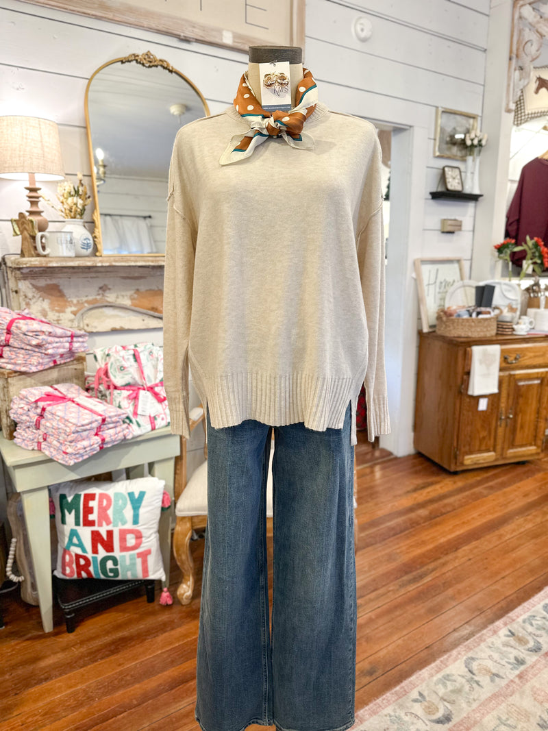 Mannequin wearing a beige sweater and blue jeans in a store setting with decorative items.