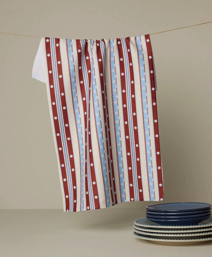Striped towel with polka dots hanging on a line, with plates stacked below.