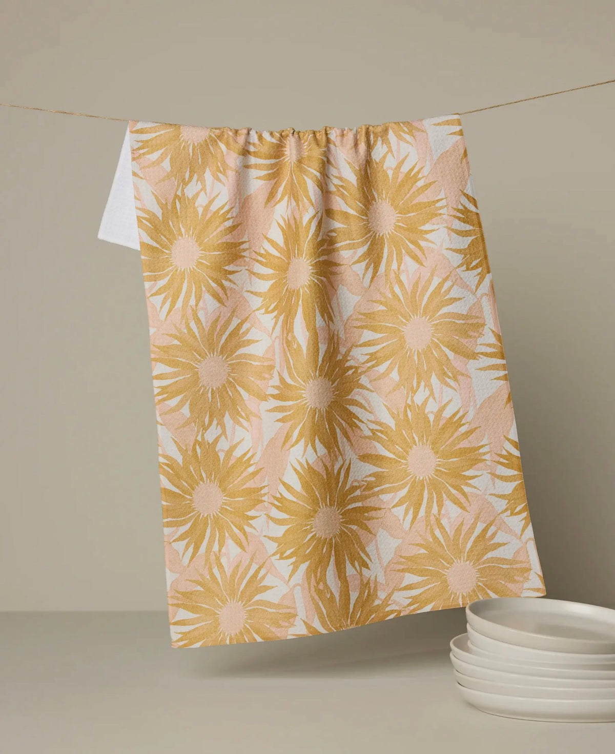 Floral patterned towel hanging on a line with plates below.