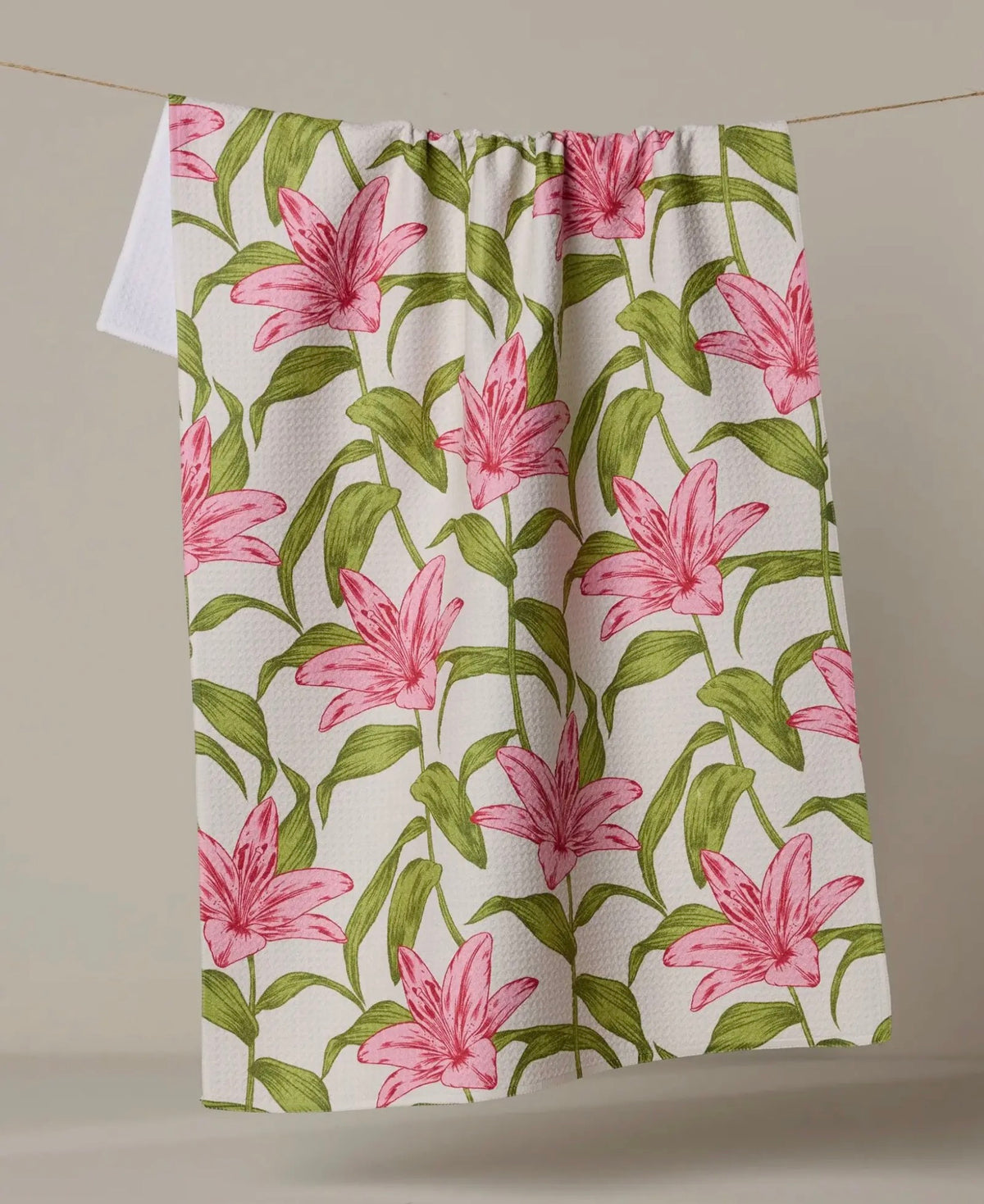 Floral patterned fabric with pink lilies and green leaves on a white background