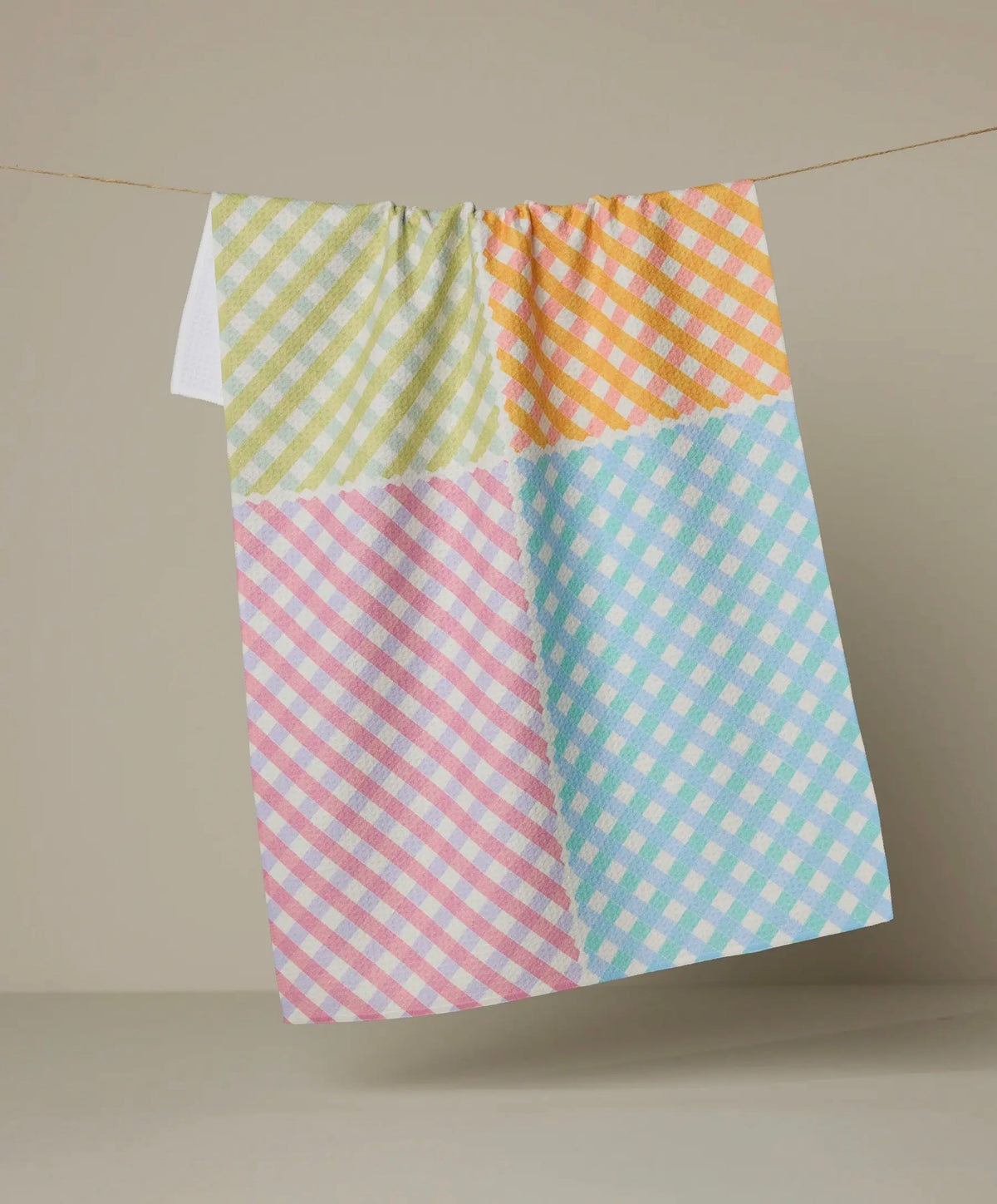 Colorful checkered towel hanging on a line against a beige background