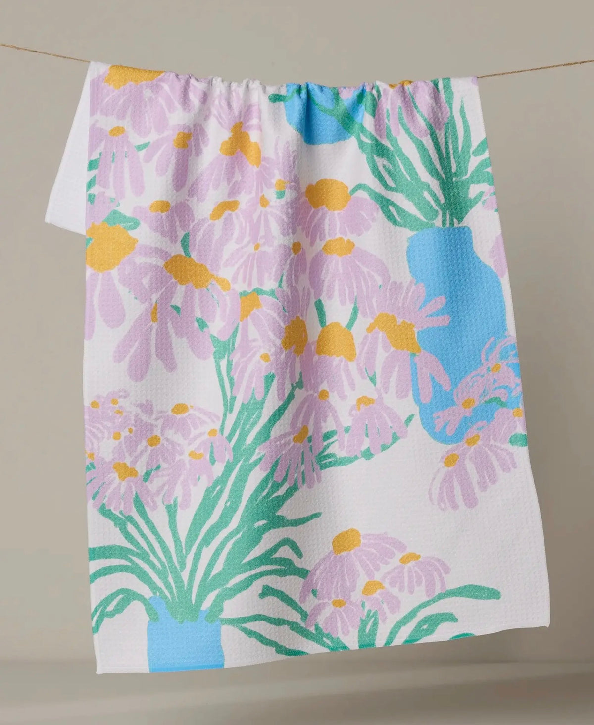 Floral patterned towel with purple flowers and green leaves on a plain background