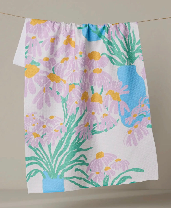 Floral patterned towel with purple flowers and green leaves on a plain background