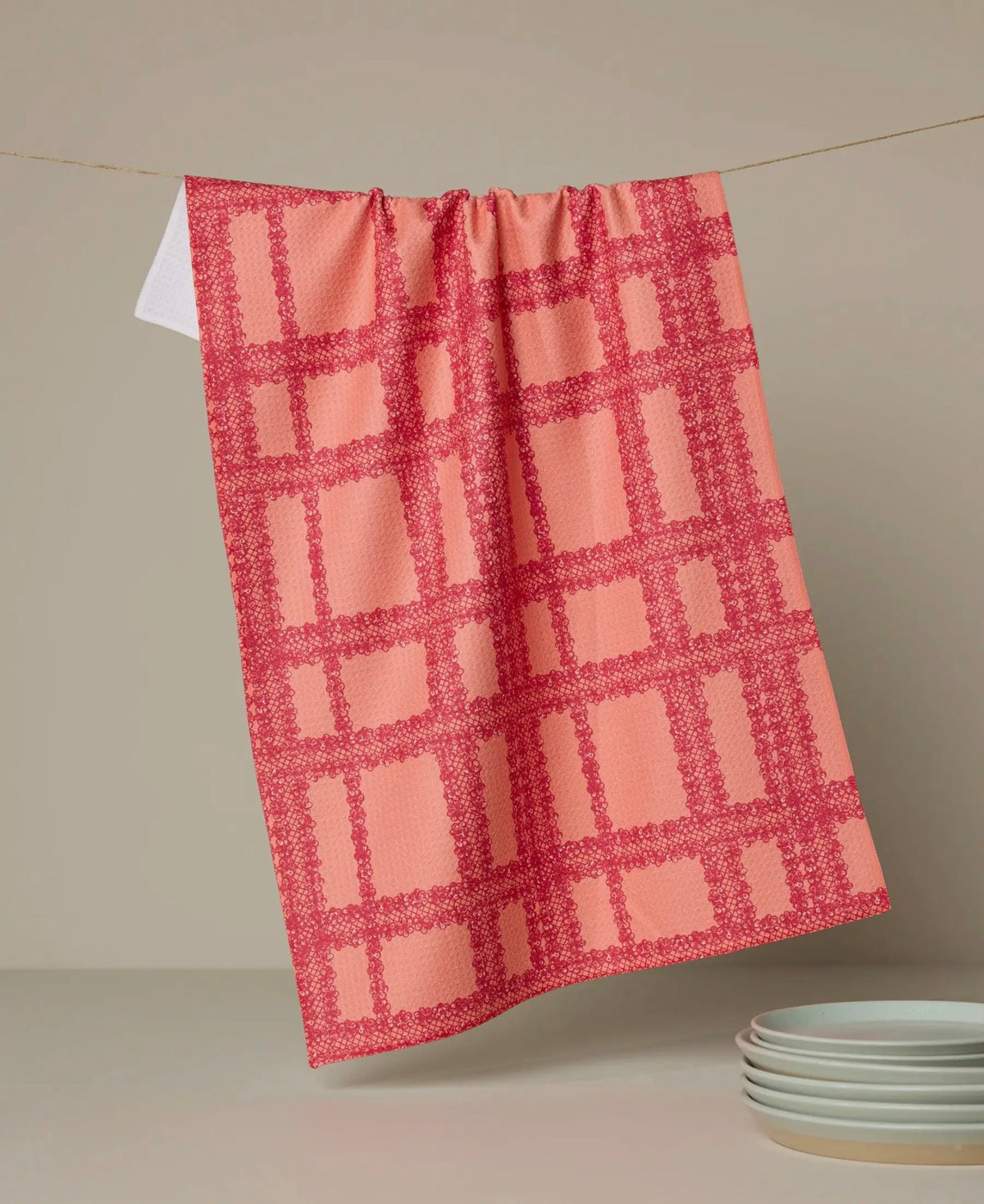 orange and pink checkered towel hanging on a line with a neutral background