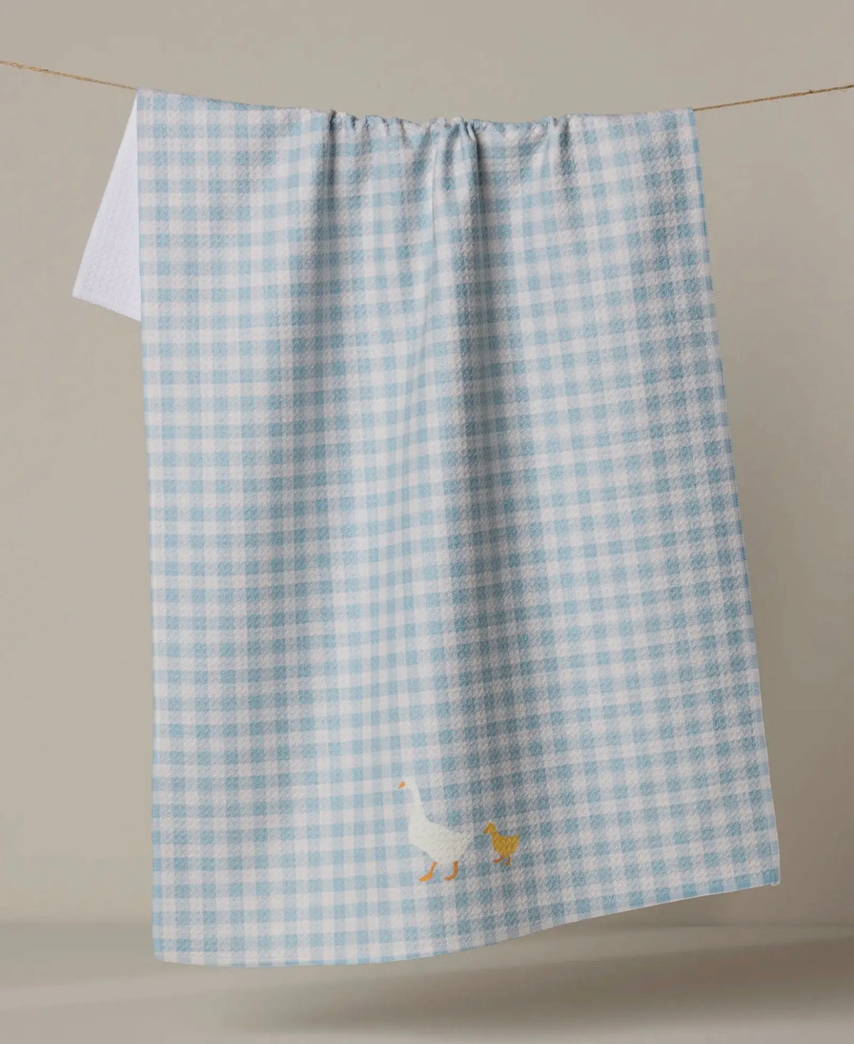 Blue and white checkered towel with  duck design on a neutral background