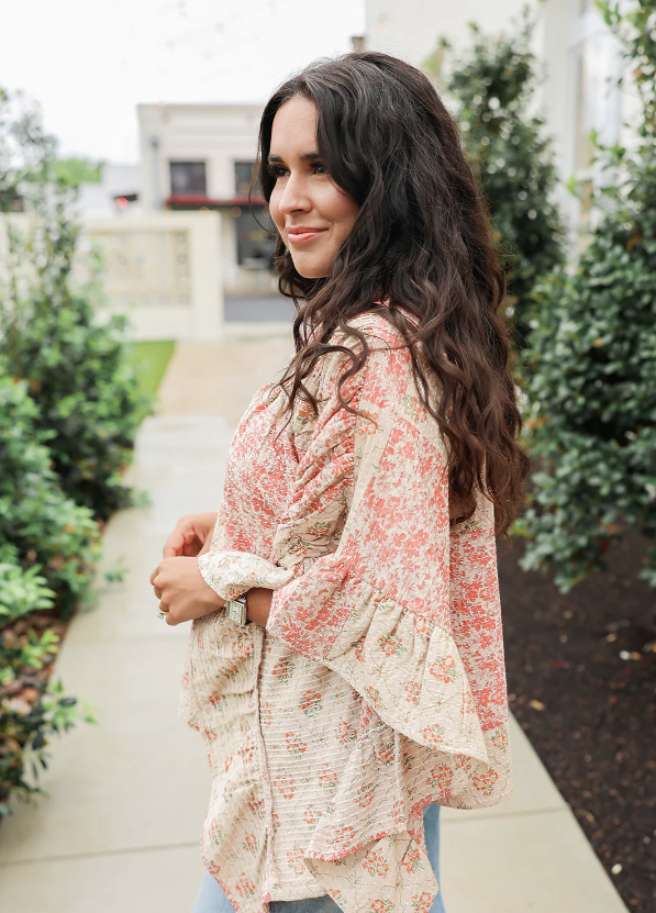 Woman wearing a floral blouse standing outdoors with greenery around
layerz clothing poncho top 