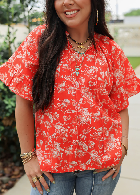 Woman wearing a red floral blouse with a blurred outdoor background
bell top red floral layerz clothing 