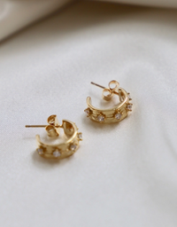 Gold hoop earrings with small stones on a light background