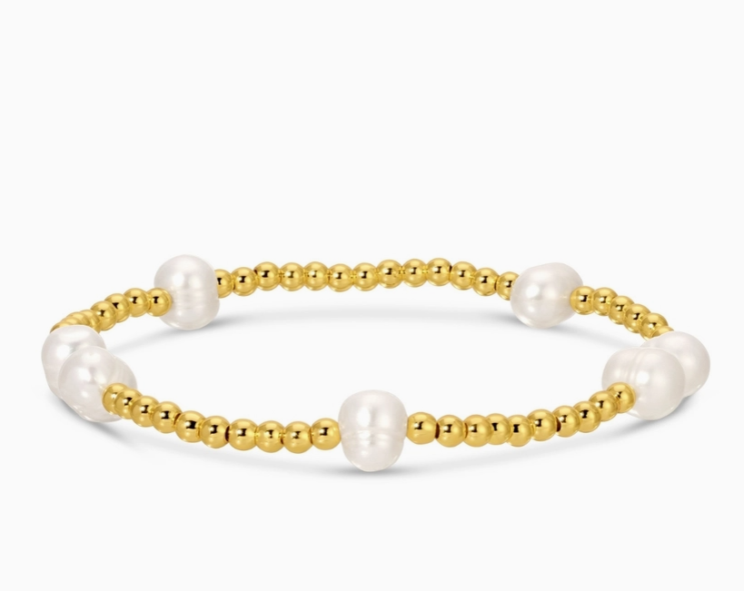 Gold bracelet with white pearls on a white background