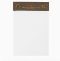 White notepad with brown cover and gold text on a white background
