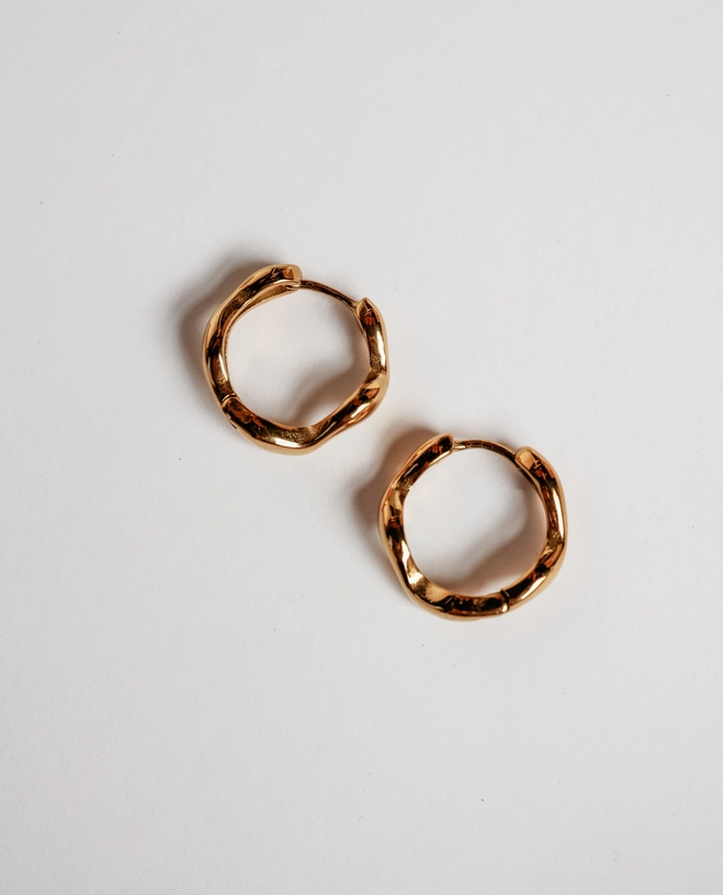 Gold hoop earrings on a light gray background