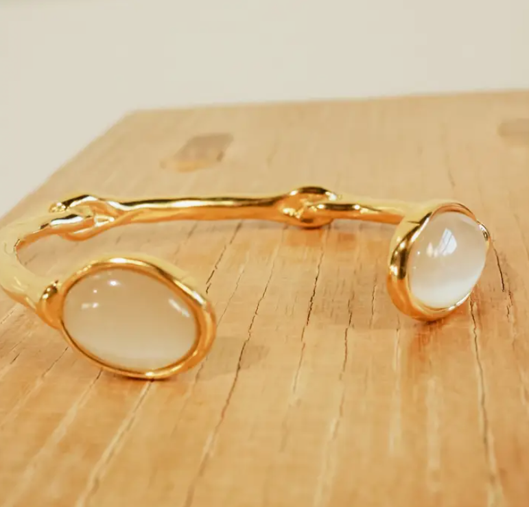 Gold bracelet with white stones on a wooden surface