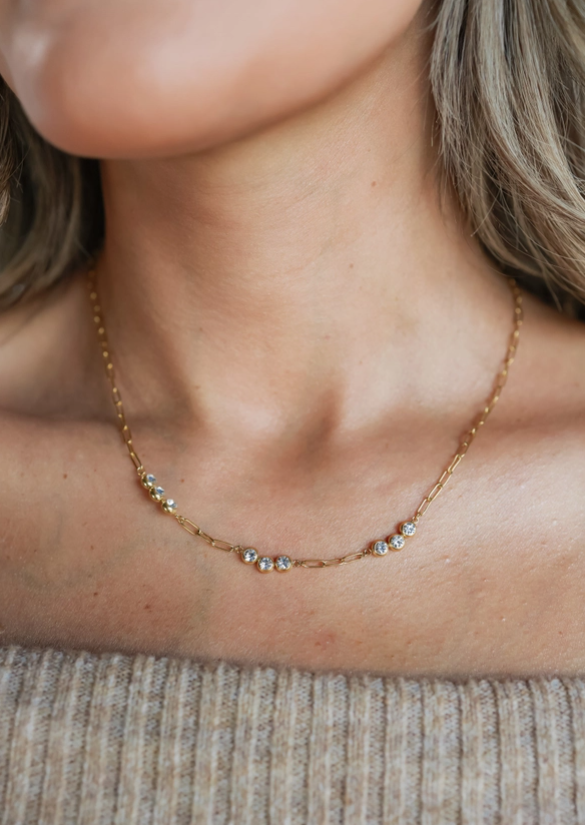 Close-up of a necklace on a person wearing a beige top.