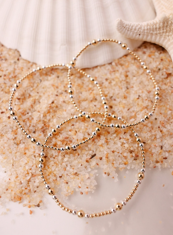 Gold beaded bracelets on a textured surface