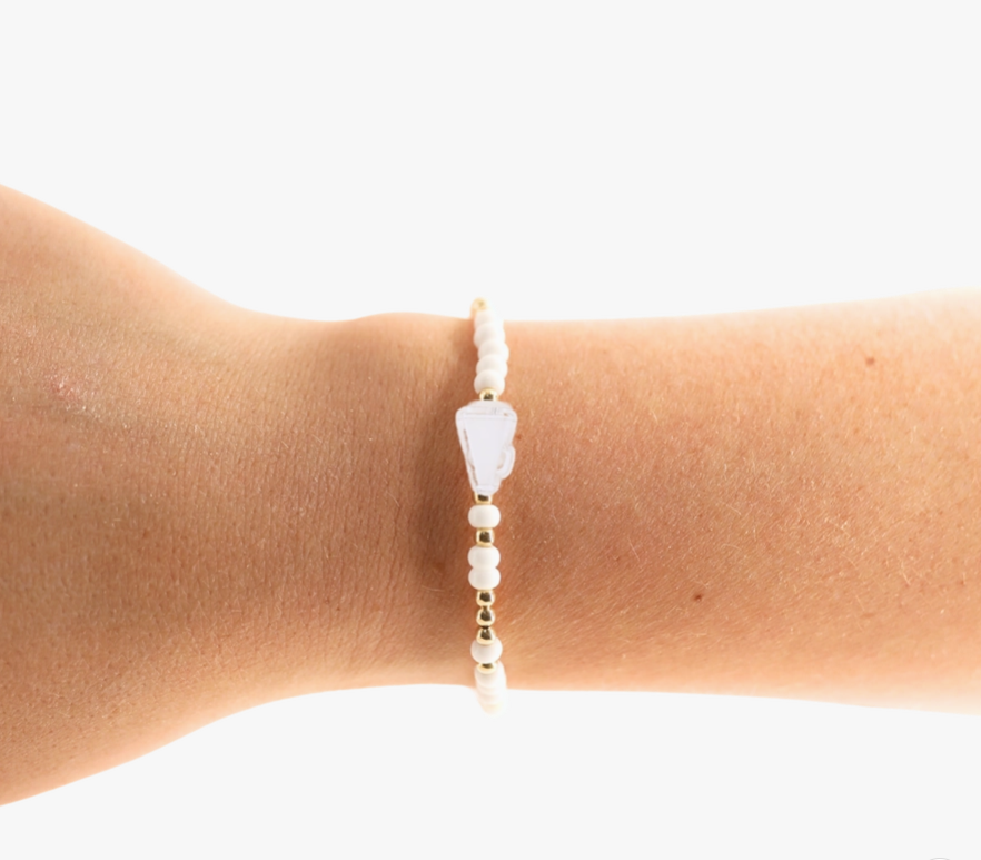 Bracelet with white beads on a wrist against a white background