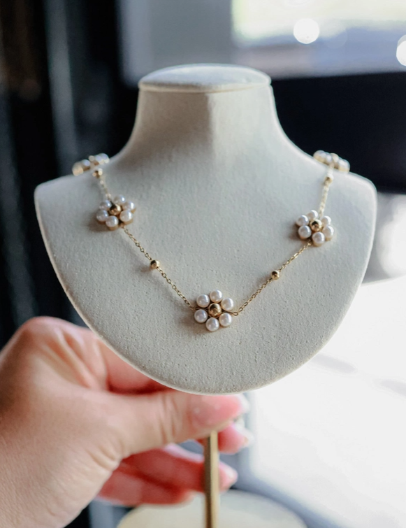 Pearl flower necklace on a mannequin held by a hand