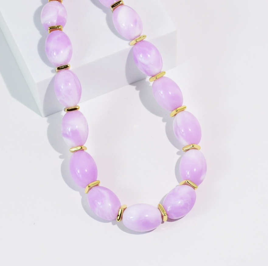 Necklace with lavender beads and gold accents on a white background