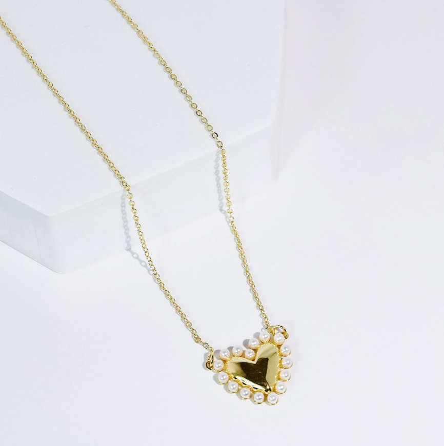 Gold necklace with a heart-shaped pendant on a white background
