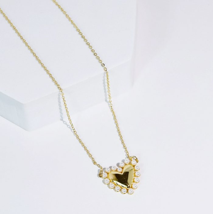 Gold necklace with a heart-shaped pendant on a white background