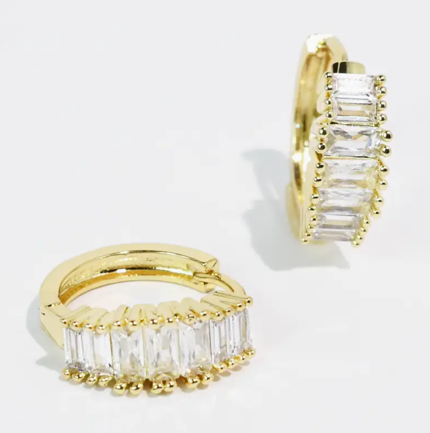 Gold hoop earrings with clear gemstones on a light gray background