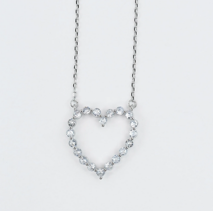 Heart-shaped necklace with clear stones on a light gray background