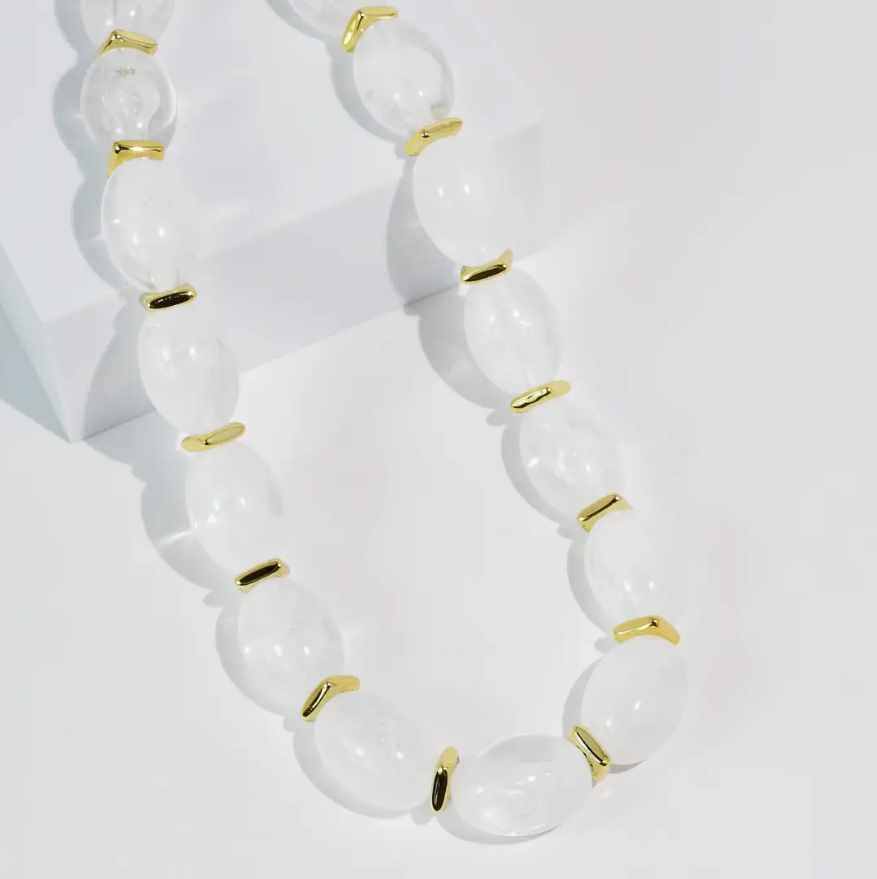 Necklace with white beads and gold accents on a light background