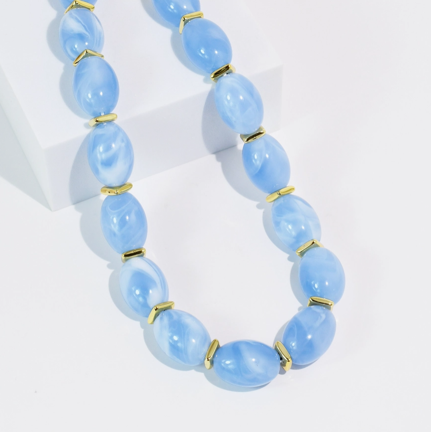 Necklace with light blue beads and gold accents on a white background